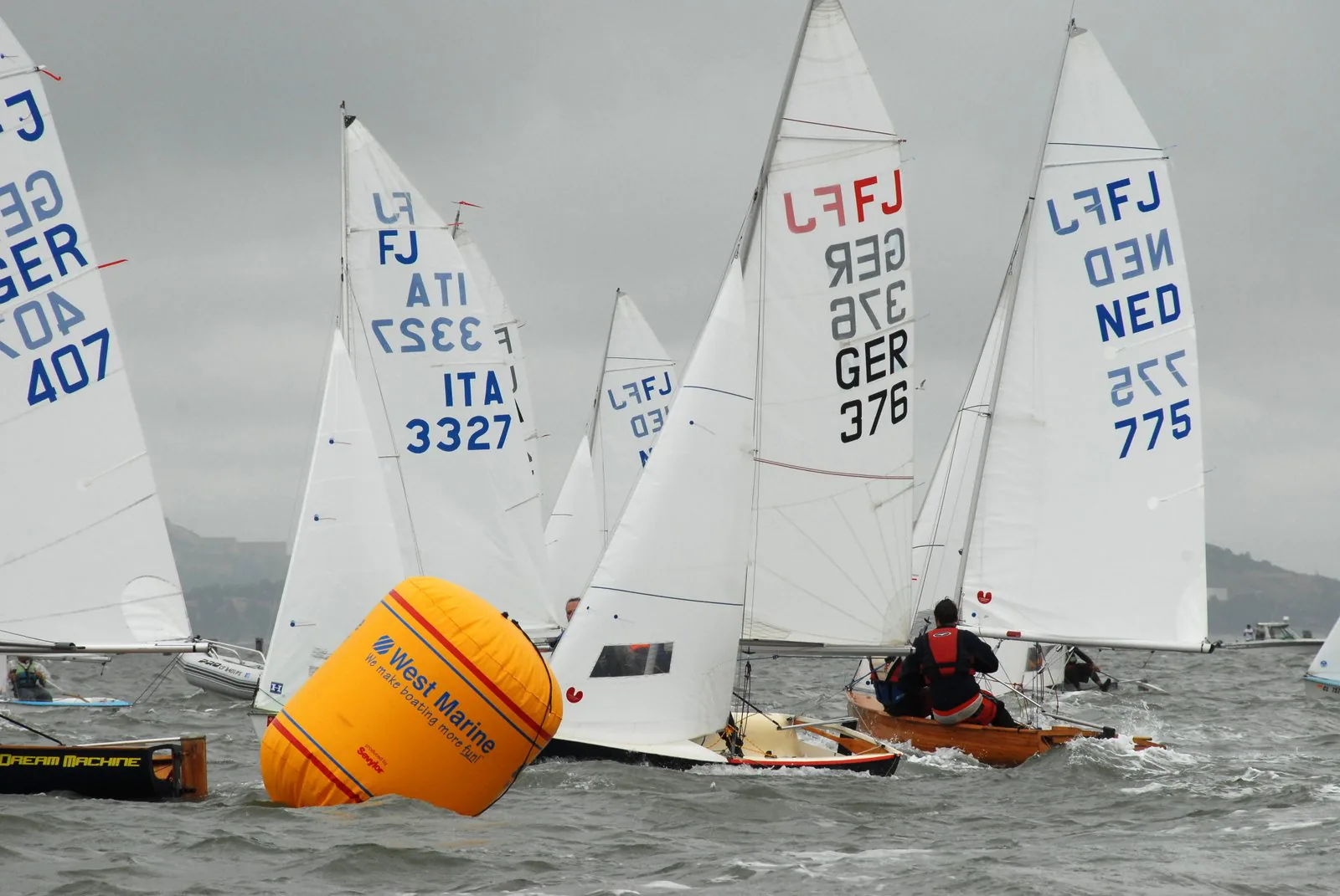 A fleet of FJ dinghies racing around an orange inflatable mark.