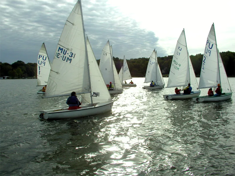 A fleet of FJ dinghies sailing on flat water.