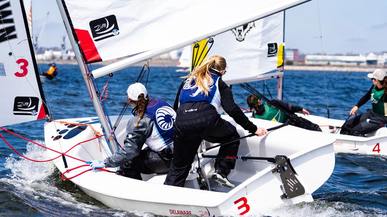 A crew of four sailors racing a doublehanded dinghy in choppy water.